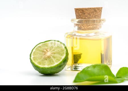 Magnifique emballage d'huile essentielle de Bergamot dans une petite bouteille de verre avec liège, fruit de bergamote frais, et feuille verte sur fond blanc. Espace vide Banque D'Images