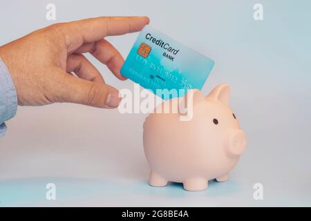 homme mettant la carte de crédit dans la banque de piggy. Le concept d'économie d'argent sur une carte de débit. Banque D'Images