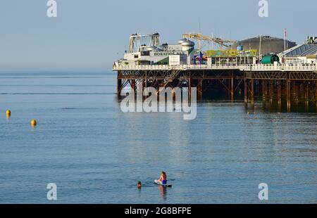 Brighton Royaume-Uni 19 juillet 2021 - UN pédalo et nageur Profitez d'une autre journée ensoleillée à Brighton car le temps chaud devrait se poursuivre au cours des prochains jours en Grande-Bretagne avec des températures qui devraient atteindre plus de 30 degrés centigrade dans certaines régions : Credit Simon Dack / Alamy Live News Banque D'Images