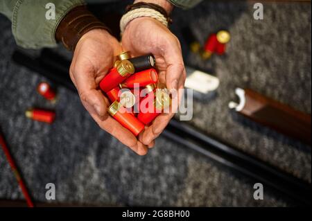 Les mains des chasseurs masculins maintiennent les cartouches dans le magasin d'armes à feu Banque D'Images