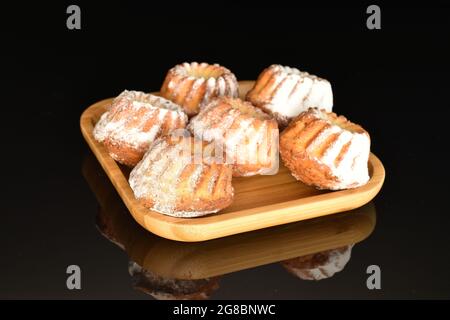 Plusieurs muffins délicieux et doux sur un plateau en bambou, en gros plan, isolés sur du noir. Banque D'Images