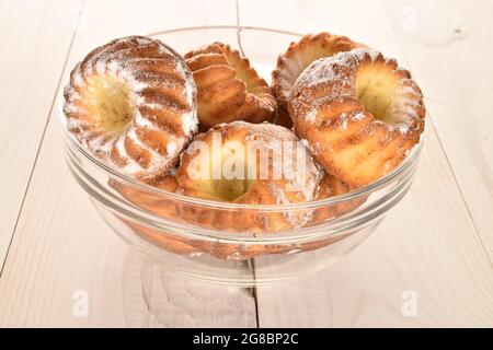 Plusieurs muffins sucrés faits maison dans un bol en verre, en gros plan, sur une table en bois blanc. Banque D'Images