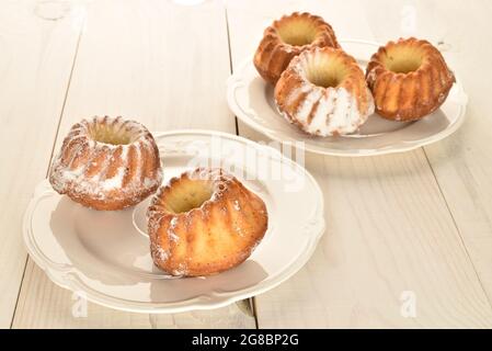 Plusieurs petits gâteaux faits maison sur deux assiettes blanches, gros plan, sur une table en bois blanc. Banque D'Images