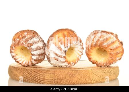 Trois muffins sucrés et savoureux sur un plateau rond en bois, gros plan, isolés sur du blanc. Banque D'Images