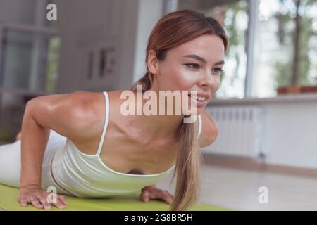 Jeune femme sur un tapis de yoga faisant la pose de la planche de dauphin Banque D'Images