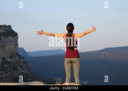 Vue arrière d'une sportswoman s'étendant des bras celebraing dans la montagne Banque D'Images