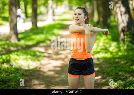 Fitness femme faisant un exercice d'étirement ses bras triceps et épaules extensible portant un tracker d'activité de montre intelligente. Les femmes s'étirent pour plus de chaleur Banque D'Images