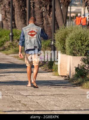 OLBIA, ITALIE - 06 juin 2021 : une vue verticale du dos d'un homme dans une tenue d'été avec une veste Harley Davidson jean Banque D'Images