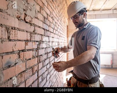 Un électricien de construction coupe un câble de tension pendant une réparation. Banque D'Images