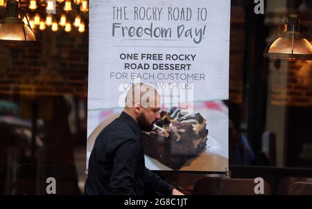 Londres, Angleterre, Royaume-Uni. 19 juillet 2021. Un homme passe devant une affiche sur le thème de la Journée de la liberté sur une fenêtre du restaurant. Presque toutes les restrictions concernant les coronavirus, y compris la distanciation sociale et le port du masque, sont levées en Angleterre à partir d'aujourd'hui. La dernière étape de la levée du verrouillage est celle du secrétaire à la Santé du pays, Sajid Javid, qui a été testé positif pour le coronavirus et le Premier ministre Boris Johnson et le chancelier Rishi Sunak, aidés par l'APP et le NHS. Démarrage de l'auto-isolation. (Image de crédit : © Tayfun Salci/ZUMA Press Wire) Banque D'Images