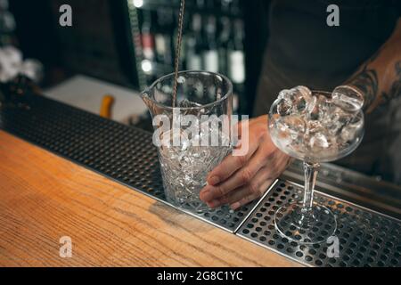 Glace dans les verres. Un barman professionnel mélangeant des cocktails avec une longue cuillère dans un pub ou un café. Gros plan Banque D'Images