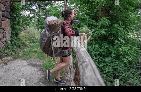 Attrayante fille touriste avec un grand sac à dos pour le voyage et avec un bouquet de fleurs sauvages. Banque D'Images