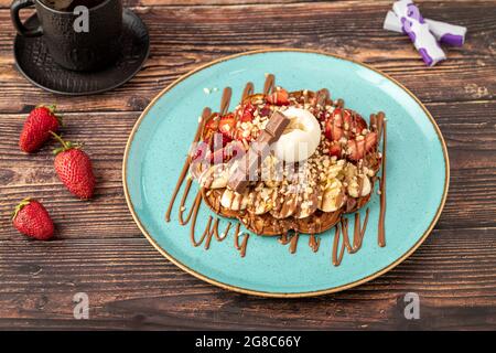 Gaufre de coeur avec banane et fraise avec bonbons délicieux et glace sur elle. Banque D'Images