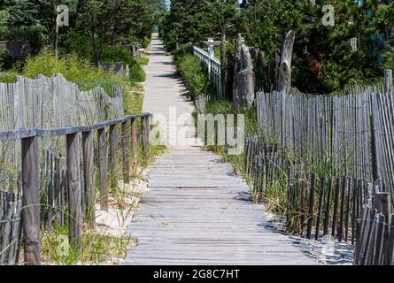 Promenade au-dessus des dunes de sable sur un chemin en bois sortant de la plage dans le quartier des maisons d'été. Banque D'Images