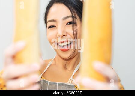 Portrait femme heureux avec le pain dans la boutique de pain, les femmes tenant le sourire de pain dans la boutique de boulangerie Banque D'Images