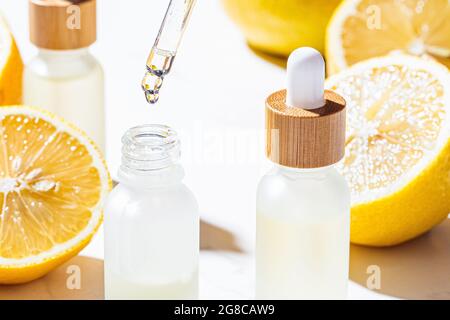 Huile essentielle de citron en bouteilles de verre, fond en marbre blanc, gros plan. Concept de soins de la peau et du corps. Banque D'Images