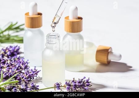 Huile essentielle de lavande en bouteilles de verre, fond en marbre blanc. Concept de soins de la peau et du corps. Banque D'Images