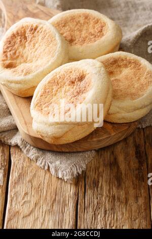 Petits pains de muffins anglais faits maison en gros plan sur une planche sur la table. Vertical Banque D'Images