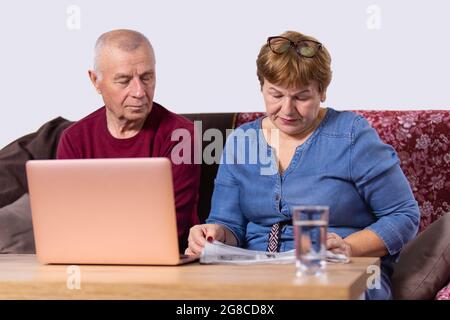 Un couple âgé se rendant dans son entreprise, une femme lisant un journal et un homme ouvrait un ordinateur portable et s'asseyant près de sa femme. Banque D'Images