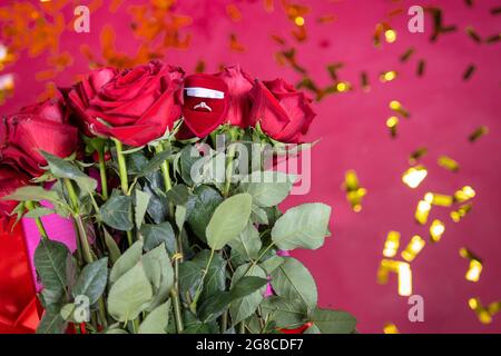 La photo des roses rouges et un beau anneau d'or sont le symbole de la proposition de mariage à une jeune femme gentille. Banque D'Images
