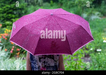 une jeune femme avec un parapluie violet dans le parc lors d'une pluie journée d'été vue de l'arrière Banque D'Images