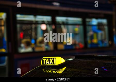 Panneau taxi la nuit dans une ville allemande avec un bus en arrière-plan Banque D'Images