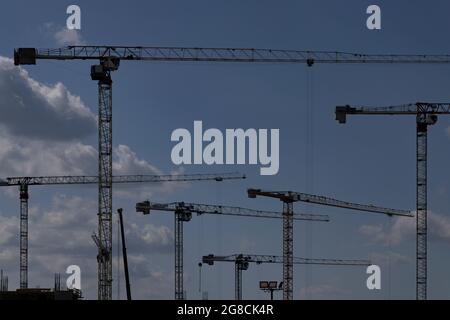 Paysage industriel avec six grues à tour en profil contre le ciel bleu Banque D'Images