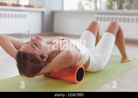 Femme faisant des exercices de rouleau de mousse pour soulager la douleur de dos. Banque D'Images