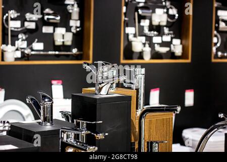 Nouveaux robinets d'eau modernes en métal pour la salle de bains sur l'exposition de magasin se dresse sur fond sombre. Banque D'Images