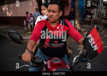 Managua, Nicaragua. 18 juillet 2021. Un homme encadre un drapeau du Front sandiniste de libération nationale (FSLN) lors d'une marche pour célébrer le 42e anniversaire du triomphe de la Révolution sandiniste et pour soutenir la Révolution cubaine. Le pays d'Amérique centrale a récemment connu une vague d'arrestations de personnalités de l'opposition. L’opposition accuse le gouvernement autoritaire du président Ortega d’avoir tenté d’éliminer d’ici quelques mois d’éventuels rivaux et critiques avant l’élection présidentielle. Crédit : Stringer/dpa/Alay Live News Banque D'Images