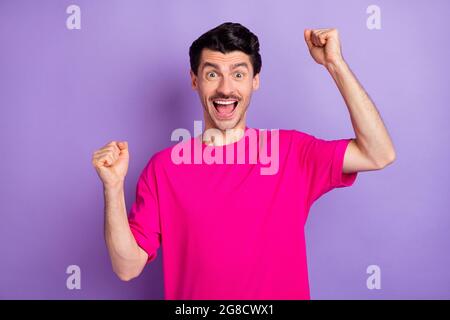 Photo d'un jeune homme chanceux impressionné habillé t-shirt rose Rising Fists isolé couleur violet fond Banque D'Images