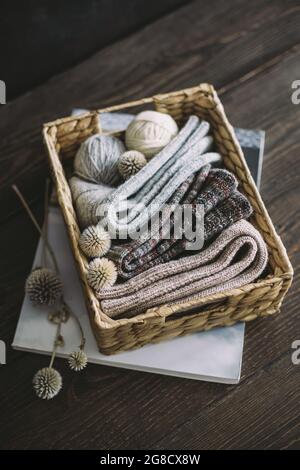 Chaussettes à tricoter à la main avec des balles de fil dans un panier sur fond de bois foncé. Concept pour la main et l'hygge vie lente. Banque D'Images