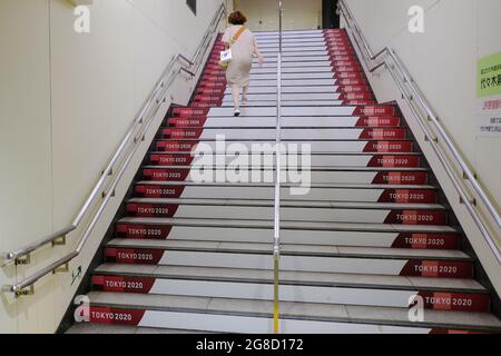 Tokyo, Japon. 15 juillet 2021. Une femme monte les escaliers avec une bannière olympique apposée à une station de métro près du stade principal des Jeux Olympiques de Tokyo en 2020. Crédit : SOPA Images Limited/Alamy Live News Banque D'Images