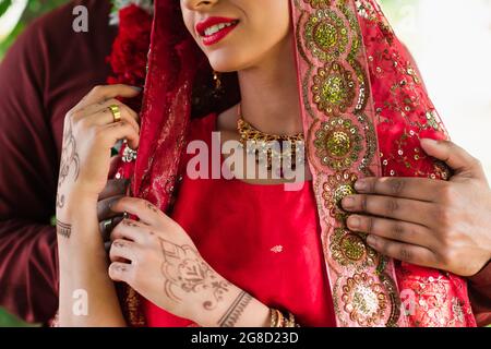 vue rognée d'un homme indien embrassant sa mariée dans le sari rouge Banque D'Images