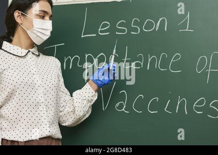 Professeur portant un masque facial et enseignant l'importance des vaccins pour la classe Banque D'Images