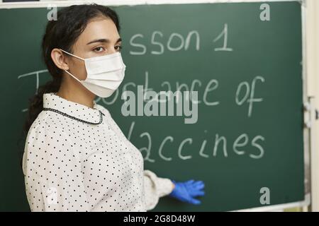 Professeur portant un masque facial et enseignant l'importance des vaccins pour la classe Banque D'Images