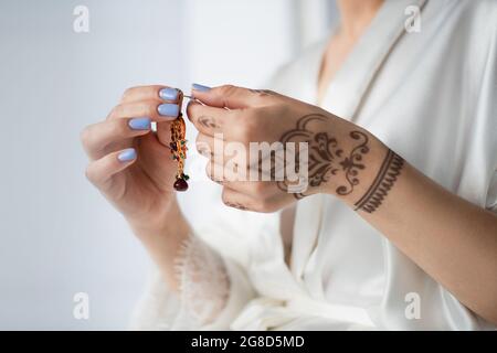 vue rognée d'une femme indienne avec des boucles d'oreilles mehndi isolées sur du blanc Banque D'Images