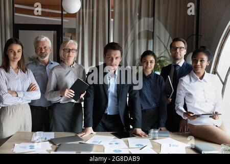 Plusieurs employés d'âge différent se tenant debout à la table de réunion Banque D'Images