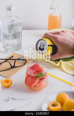 Cocktail rouge avec cubes de pastèque congelés, gin et soda. Versez le soda à la main dans le verre à boire Banque D'Images