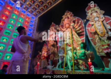 Image floue du jeune prêtre hindou bengali adorables déesse Durga avec chamor, Durga aarti sous la fumée sainte pendant Durga Puja tourné la nuit. Banque D'Images