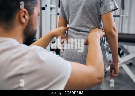 L'homme de chiropracteur vérifie la posture incorrecte de la petite fille vue de dos. Physiothérapeute homme Banque D'Images