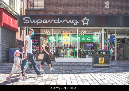 Belfast, Royaume-Uni. 18 juillet 2021. Une famille passe par le détaillant Supermed Health & Beauty sur Ann Street. Crédit : SOPA Images Limited/Alamy Live News Banque D'Images