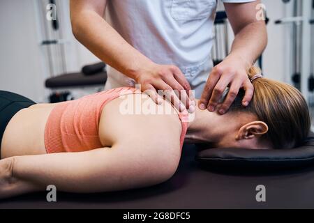 Jeune femme se fait masser le cou, la tête dans la salle de thérapie. Masseur faisant le traitement chiropratique Banque D'Images