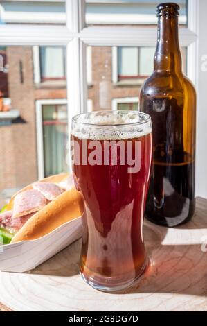 Boire de la bière foncée avec sandwich au poisson fumé à l'anguille avec vue sur la rue dans la vieille ville de Zierikzee, Zeeland, pays-Bas, gros plan Banque D'Images