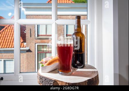 Boire de la bière foncée avec sandwich au poisson fumé à l'anguille avec vue sur la rue dans la vieille ville de Zierikzee, Zeeland, pays-Bas, gros plan Banque D'Images