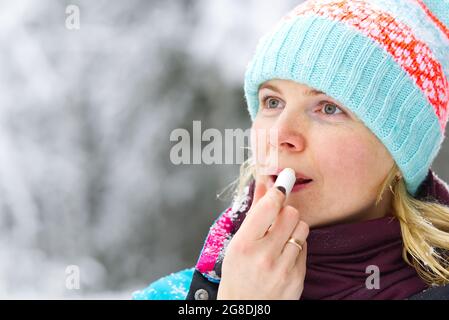 les filles utilise le rouge à lèvres hygiénique dehors en hiver dans le gel. les soins des lèvres les jours de gel Banque D'Images