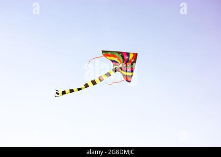 Un cerf-volant multicolore aux couleurs vives vole dans le vent en hauteur dans le ciel. Animations pour les enfants, activités de plein air pour les enfants en été. Un concept de liberté, j Banque D'Images