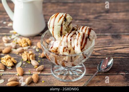 Glace Roma aux amandes, pistaches et noix dans un bol en verre avec sauce caramel. Banque D'Images