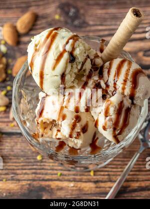 Glace Roma aux amandes, pistaches et noix dans un bol en verre avec sauce caramel. Banque D'Images