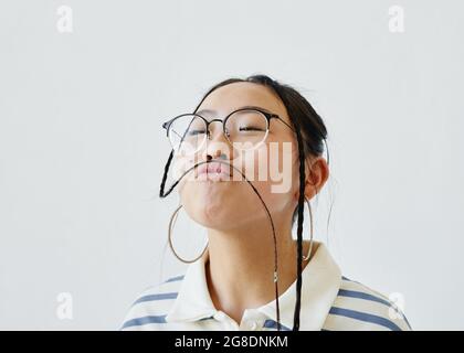 Portrait de petite taille d'une adolescente insouciante s'amusant et se faisant des visages tout en se tenant sur fond blanc, espace de copie Banque D'Images